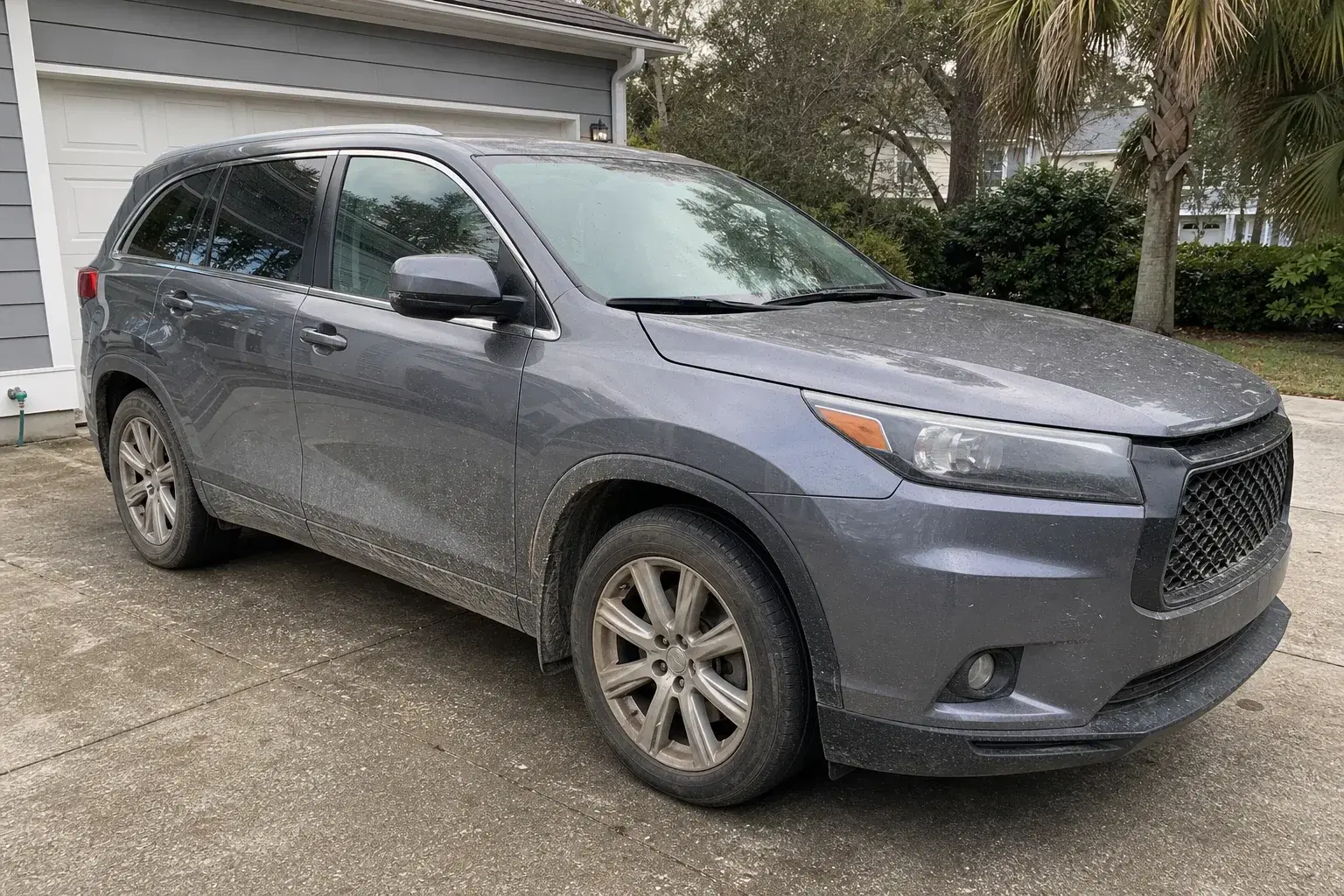 Gray family SUV with visible road film and dirty wheels before a mobile exterior detail