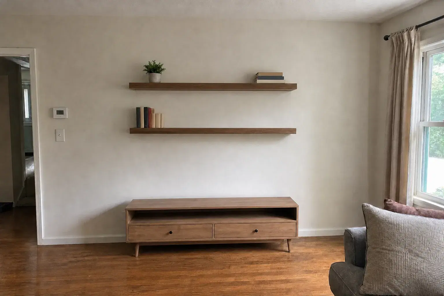 The same living-room wall with two level walnut floating shelves neatly installed