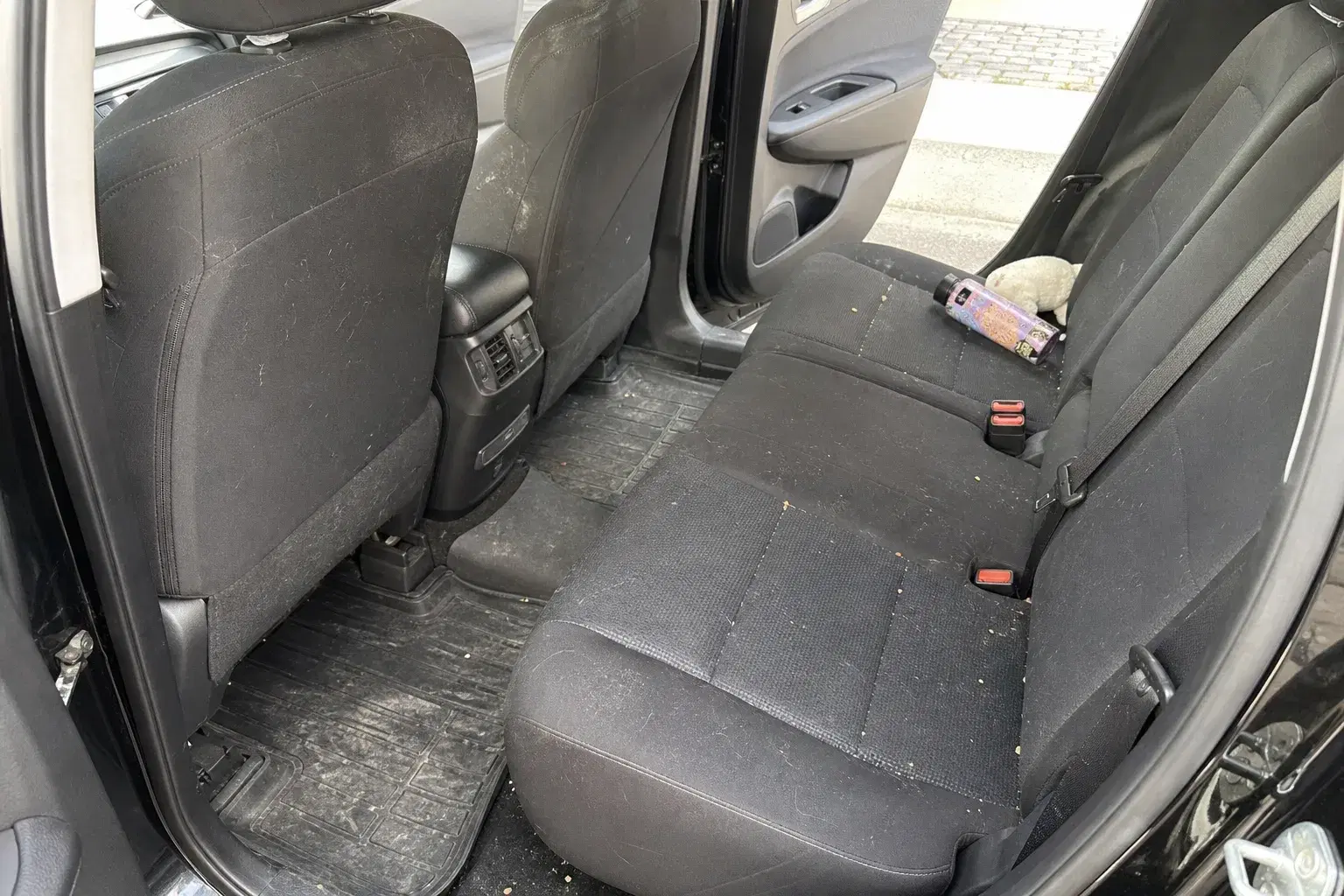 Everyday vehicle cabin with dust, crumbs, and light clutter before an interior detail