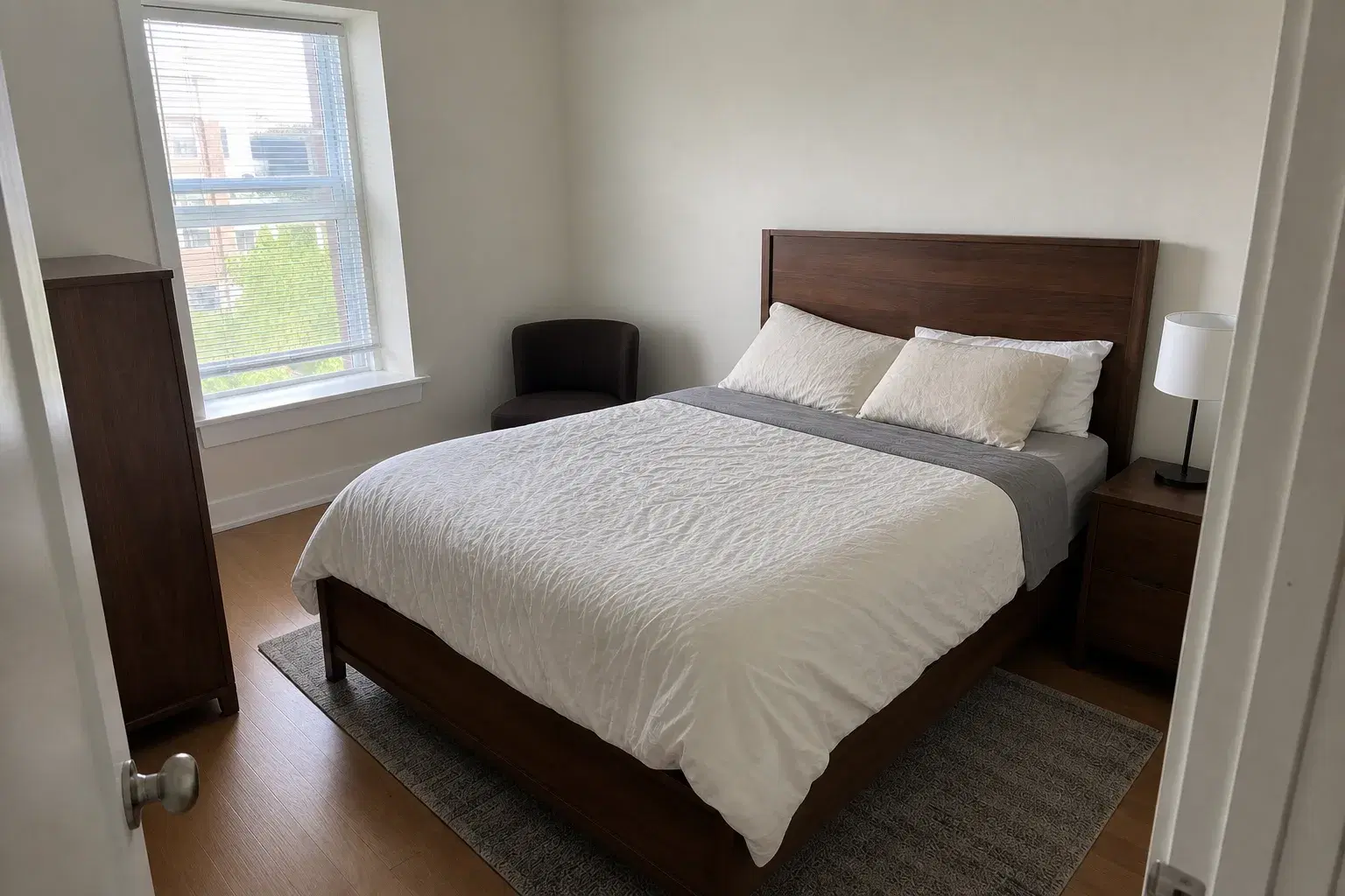 The same apartment bedroom with a neatly made bed and clean clear surfaces